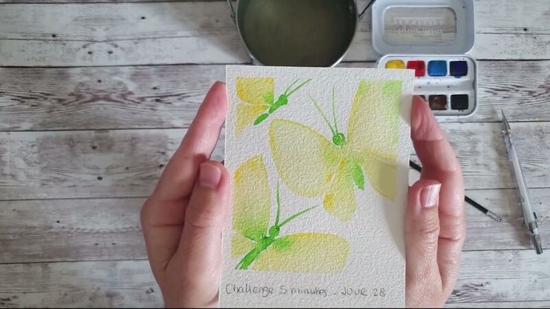 Petite aquarelle de trois papillons aux ailes jaune pâle et au corps vert vif, tenue à deux mains.