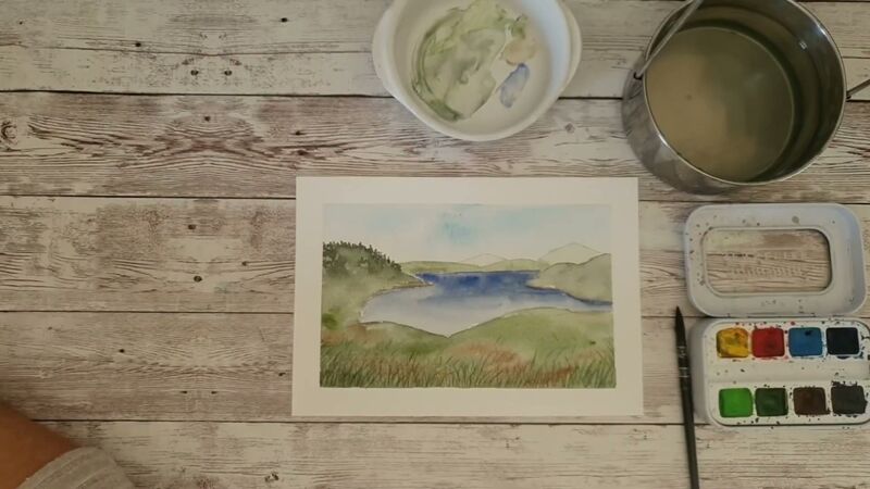 Paysage à l'aquarelle : ciel bleu pâle, collines vertes successives, lac bleu outremer et premier plan d'herbes.
